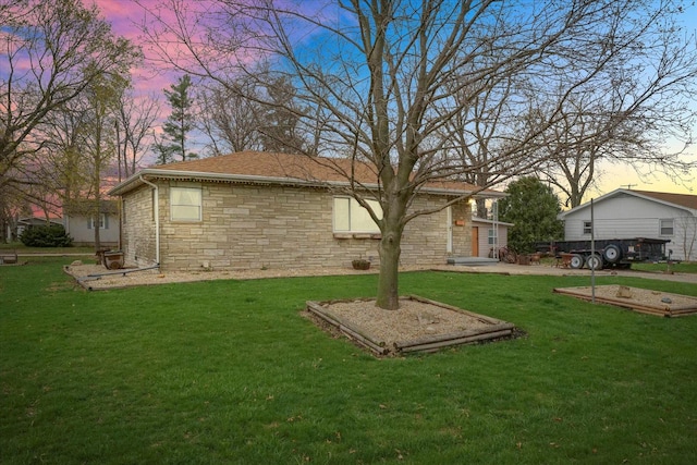 back of house with a yard, stone siding, and roof with shingles