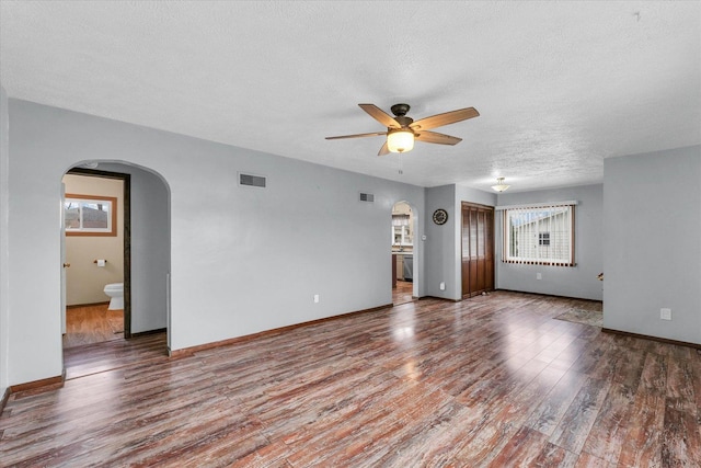spare room featuring visible vents, arched walkways, a ceiling fan, a textured ceiling, and wood finished floors
