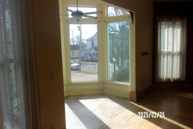 doorway with a ceiling fan and baseboards