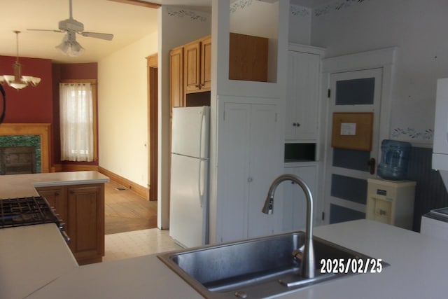 kitchen with freestanding refrigerator, pendant lighting, light countertops, and a sink