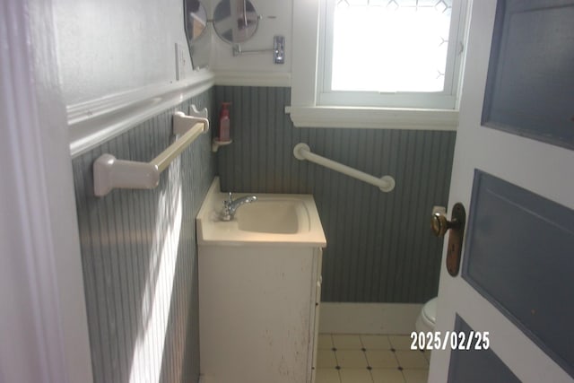 half bath featuring vanity, toilet, and tile patterned floors