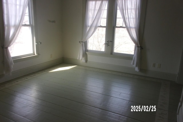 empty room with a healthy amount of sunlight, baseboards, and wood finished floors