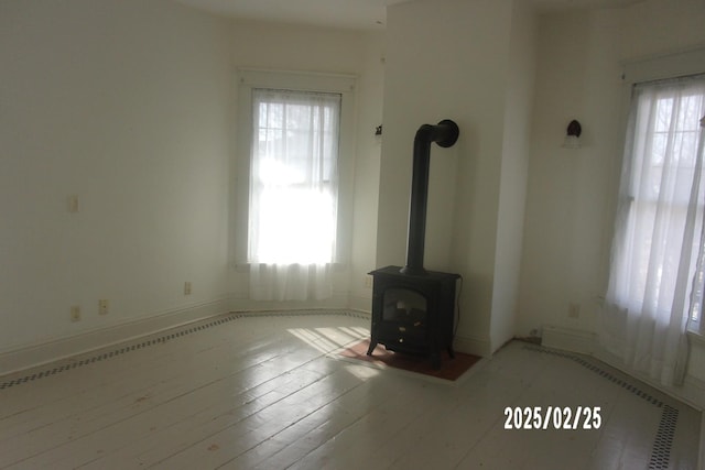 unfurnished living room with a wood stove and light wood-style flooring