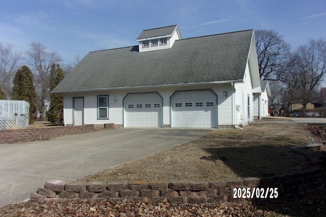 view of side of home featuring a garage, a shingled roof, and concrete driveway