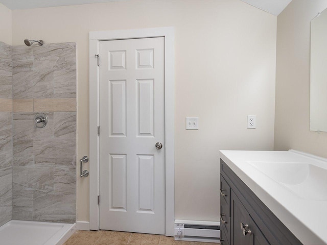 bathroom with tiled shower, baseboard heating, vanity, and tile patterned floors