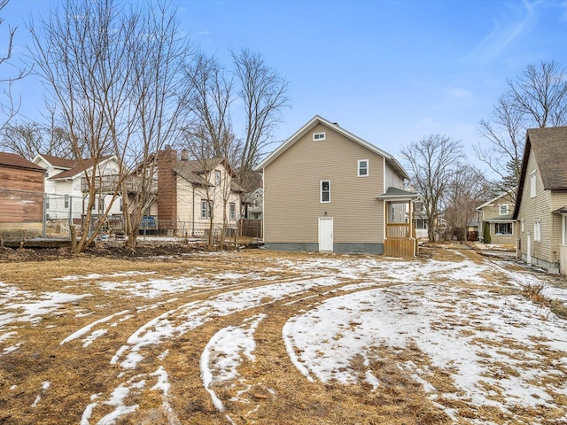 snow covered property featuring fence and a residential view