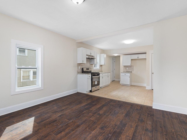 kitchen featuring white cabinetry, light countertops, decorative backsplash, light wood finished floors, and gas range