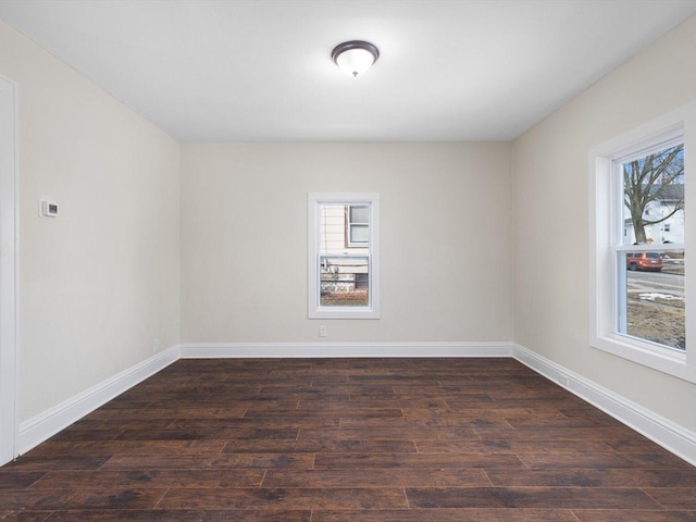 empty room with plenty of natural light, dark wood finished floors, and baseboards