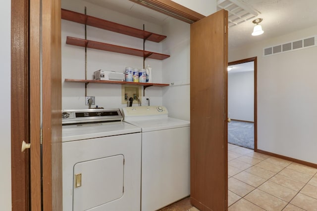 laundry room featuring washing machine and clothes dryer, light tile patterned floors, visible vents, laundry area, and baseboards