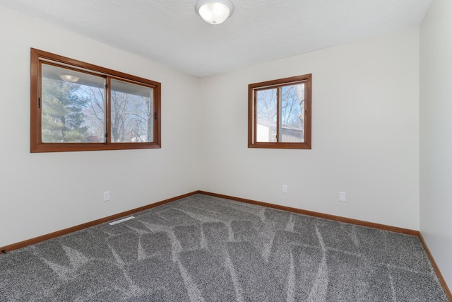 unfurnished room with carpet flooring, visible vents, and baseboards