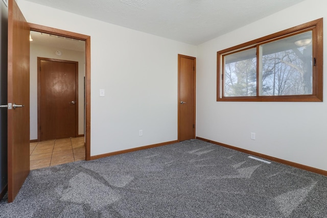 unfurnished bedroom featuring carpet, a textured ceiling, and baseboards