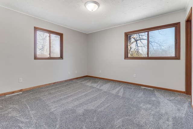 spare room featuring a textured ceiling, carpet flooring, and baseboards