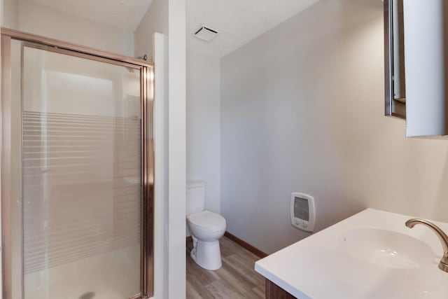 bathroom featuring visible vents, toilet, wood finished floors, vanity, and a shower stall