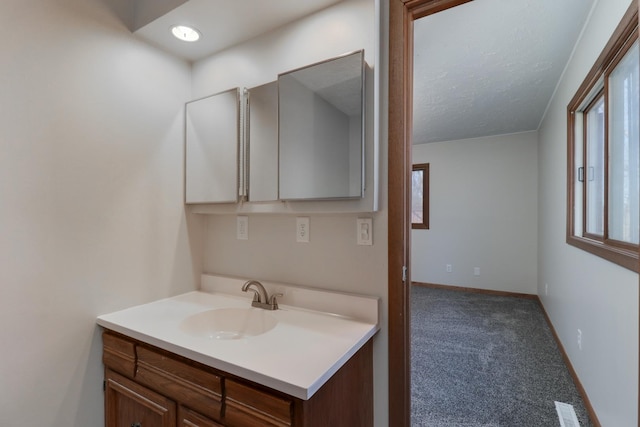 bathroom featuring a textured ceiling, vanity, visible vents, and baseboards