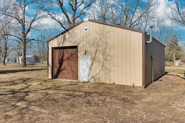 view of outdoor structure with dirt driveway and an outbuilding