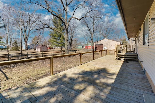 wooden deck featuring a shed, an outdoor structure, and fence