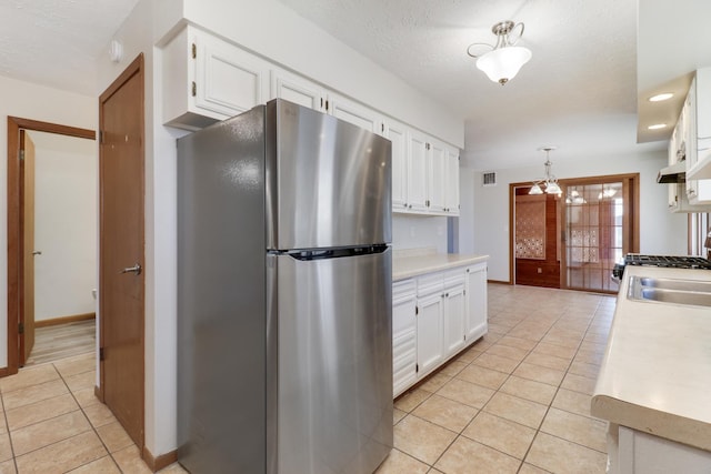 kitchen with light tile patterned floors, light countertops, visible vents, freestanding refrigerator, and white cabinetry