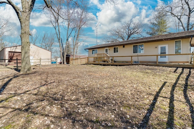 back of house with fence, a deck, and an outbuilding