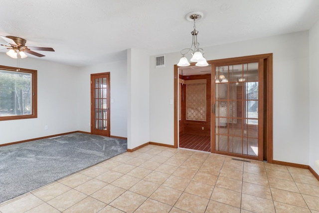 spare room featuring light tile patterned floors, ceiling fan with notable chandelier, visible vents, and baseboards