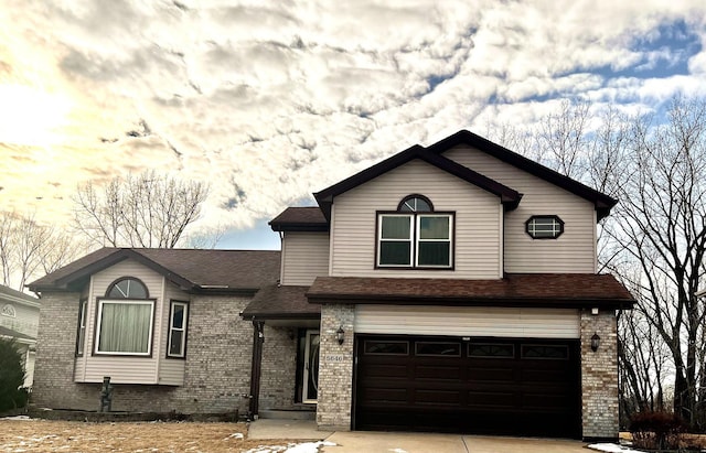 view of front of house featuring a shingled roof, brick siding, driveway, and an attached garage