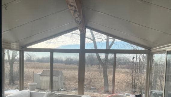 unfurnished sunroom featuring lofted ceiling, a rural view, and a healthy amount of sunlight