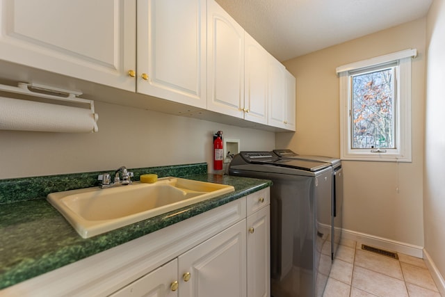 washroom featuring cabinet space, visible vents, independent washer and dryer, a sink, and light tile patterned flooring