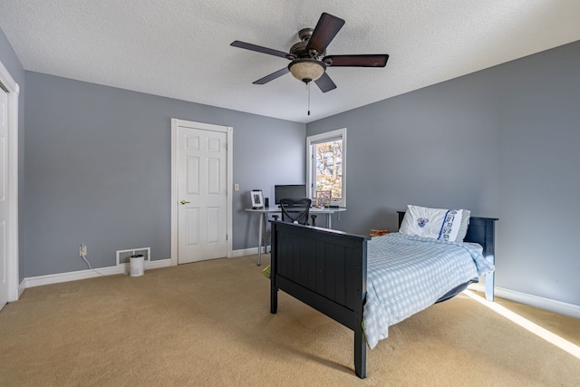 bedroom featuring light carpet, a textured ceiling, and baseboards