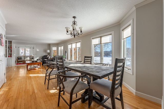 dining room with light wood-type flooring, crown molding, and an inviting chandelier