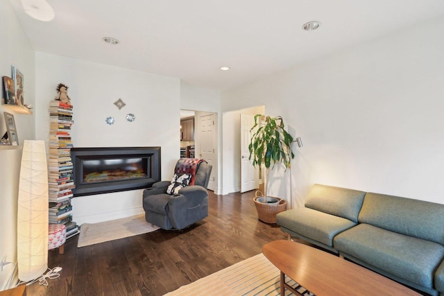 living area featuring a glass covered fireplace, baseboards, recessed lighting, and wood finished floors