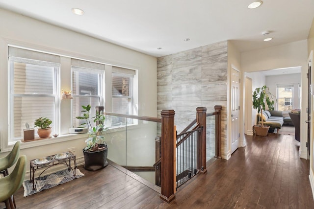 corridor featuring recessed lighting, wood-type flooring, an upstairs landing, and tile walls