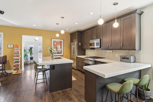 kitchen featuring dark wood-style floors, tasteful backsplash, a breakfast bar area, and stainless steel appliances