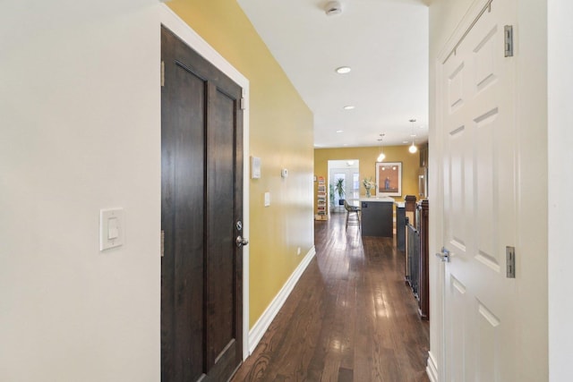 hallway with an upstairs landing, baseboards, dark wood-type flooring, and recessed lighting