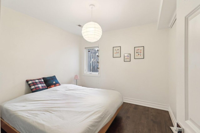 bedroom with dark wood-style floors and baseboards