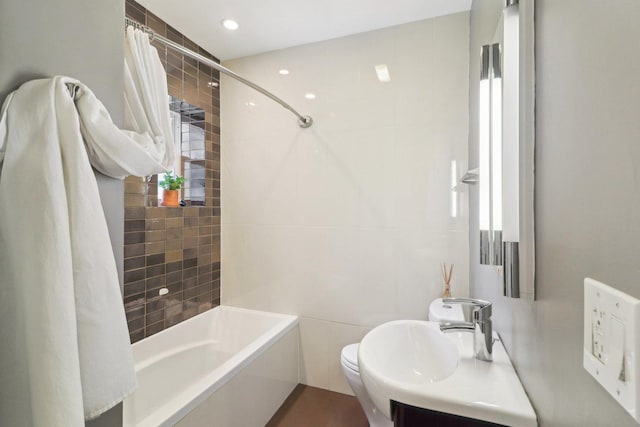 bathroom featuring tile walls, recessed lighting, shower / bathtub combination with curtain, toilet, and a sink