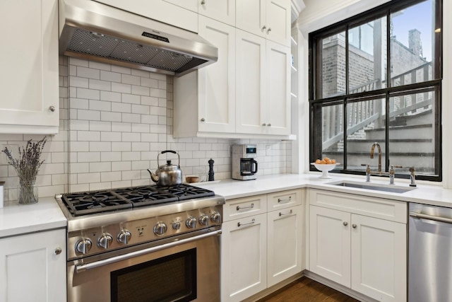 kitchen with a sink, stainless steel appliances, under cabinet range hood, white cabinetry, and backsplash