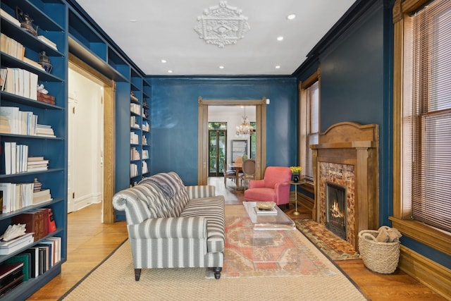 living area with light wood finished floors, crown molding, a chandelier, a premium fireplace, and recessed lighting