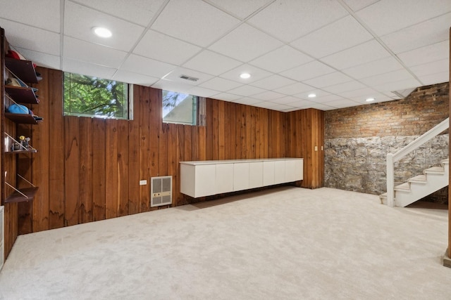 below grade area with stairs, visible vents, carpet floors, and wood walls