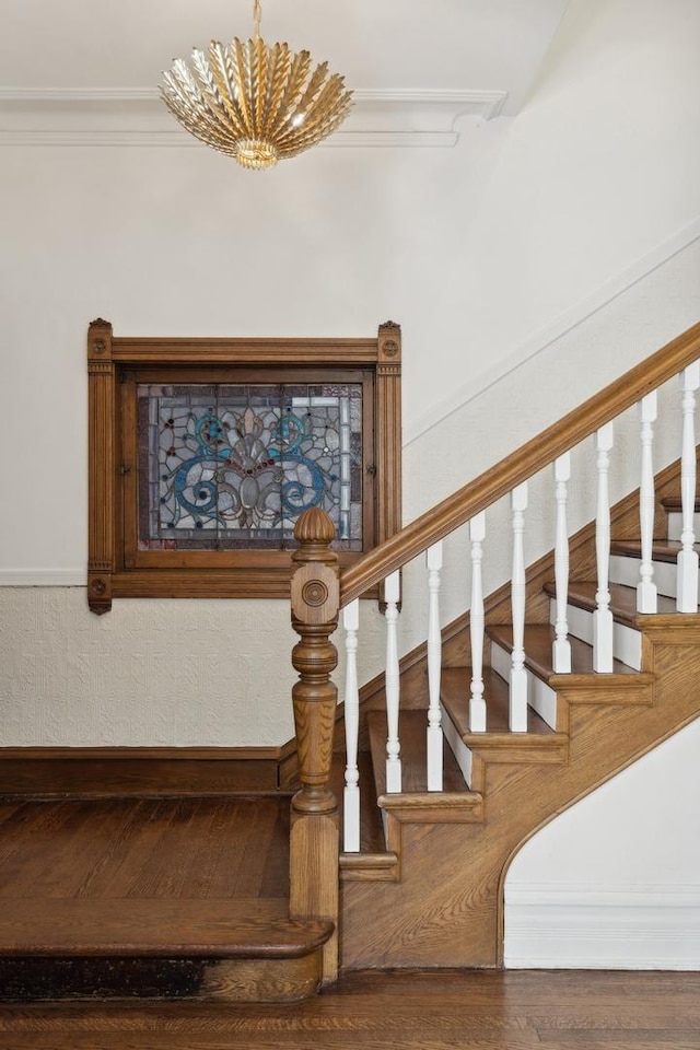 stairway featuring a chandelier, ornamental molding, and wood finished floors