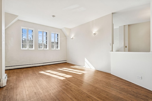 spare room featuring a baseboard radiator, a baseboard heating unit, baseboards, and wood-type flooring