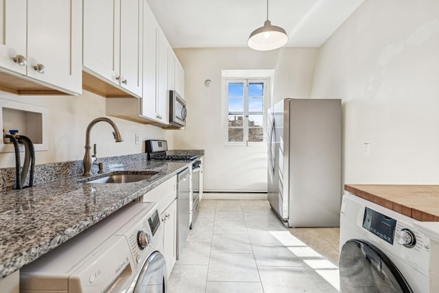 kitchen with light stone counters, appliances with stainless steel finishes, washer / clothes dryer, and a sink