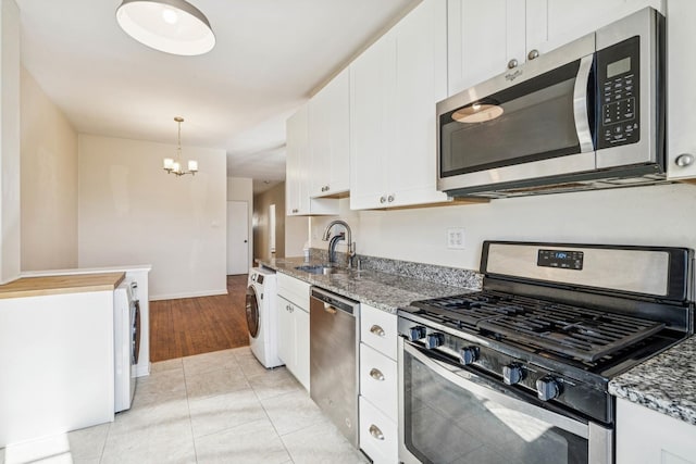 kitchen with stone counters, stainless steel appliances, washer / dryer, and a sink