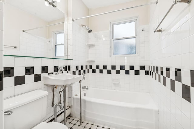 full bath featuring tile patterned floors, toilet, a sink, tile walls, and bathtub / shower combination