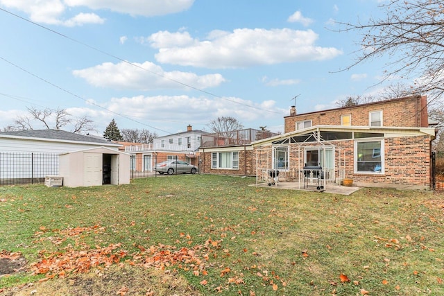 back of house featuring an outbuilding, a patio, brick siding, a lawn, and a shed