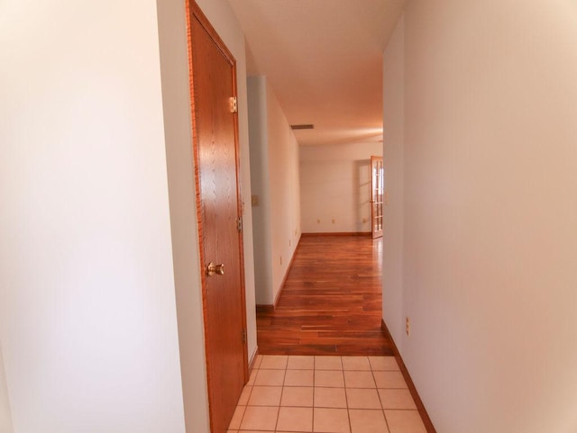 corridor with baseboards and light tile patterned floors