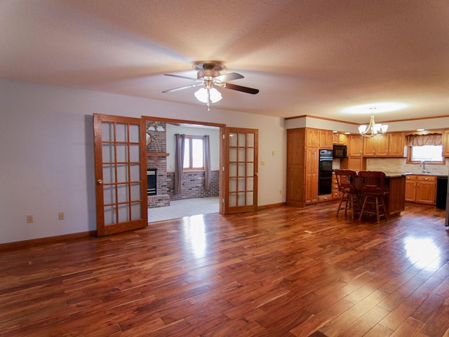 unfurnished living room with a wealth of natural light, dark wood-style flooring, a fireplace, and a sink