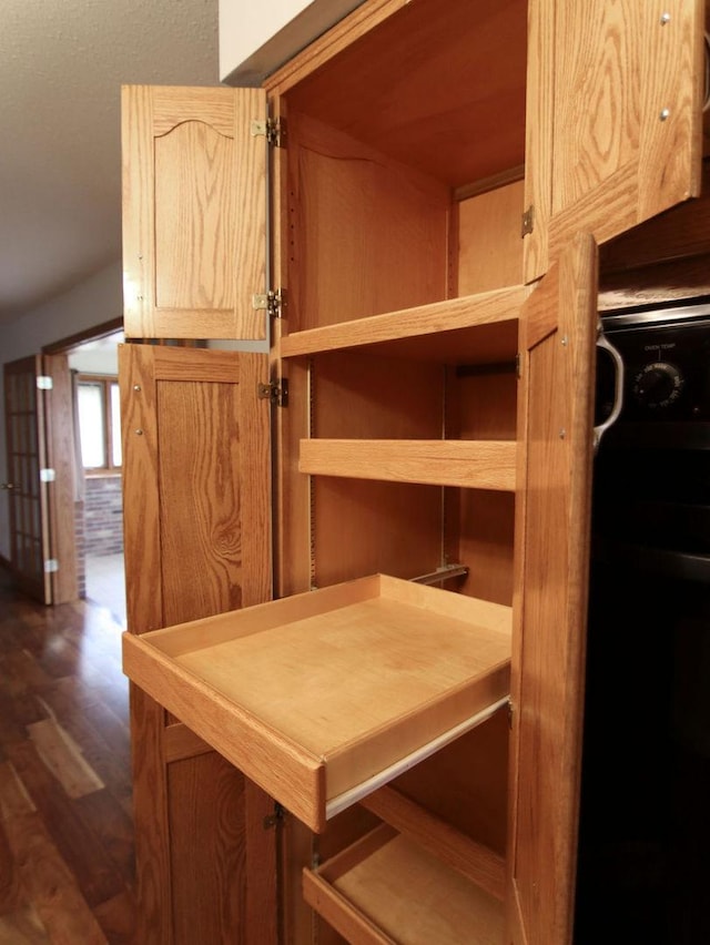 room details featuring dark wood-style flooring, stove, and light brown cabinets