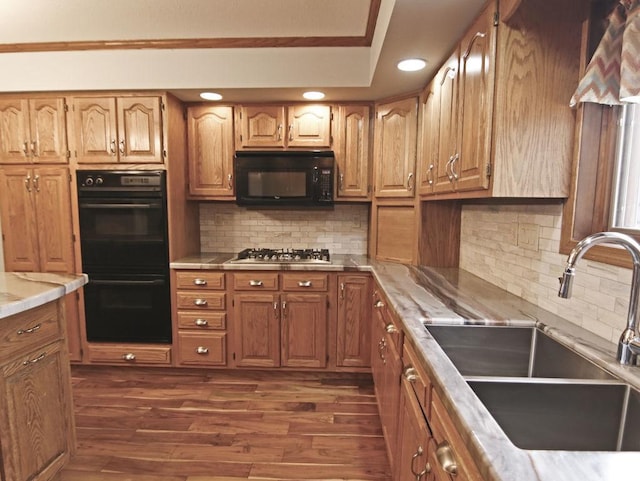 kitchen with a sink, light countertops, backsplash, dark wood-style floors, and black appliances