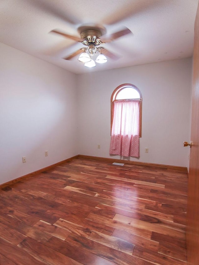 unfurnished room with dark wood-style floors, baseboards, and a ceiling fan