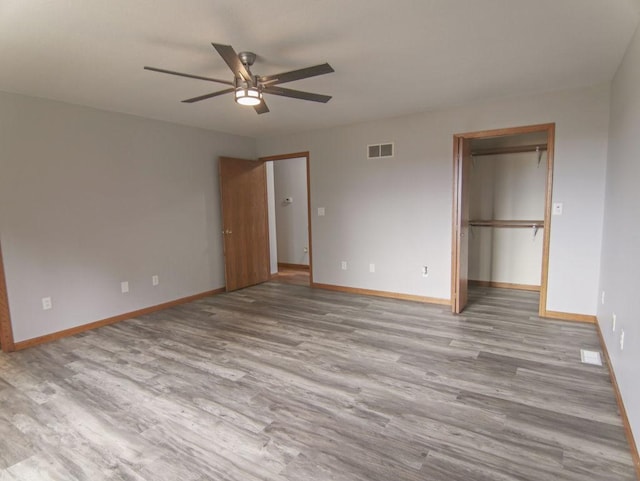 unfurnished bedroom featuring a closet, visible vents, light wood-style floors, a ceiling fan, and baseboards