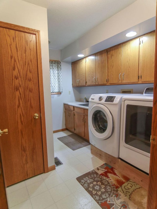 washroom with cabinet space, baseboards, washer and dryer, light floors, and a sink